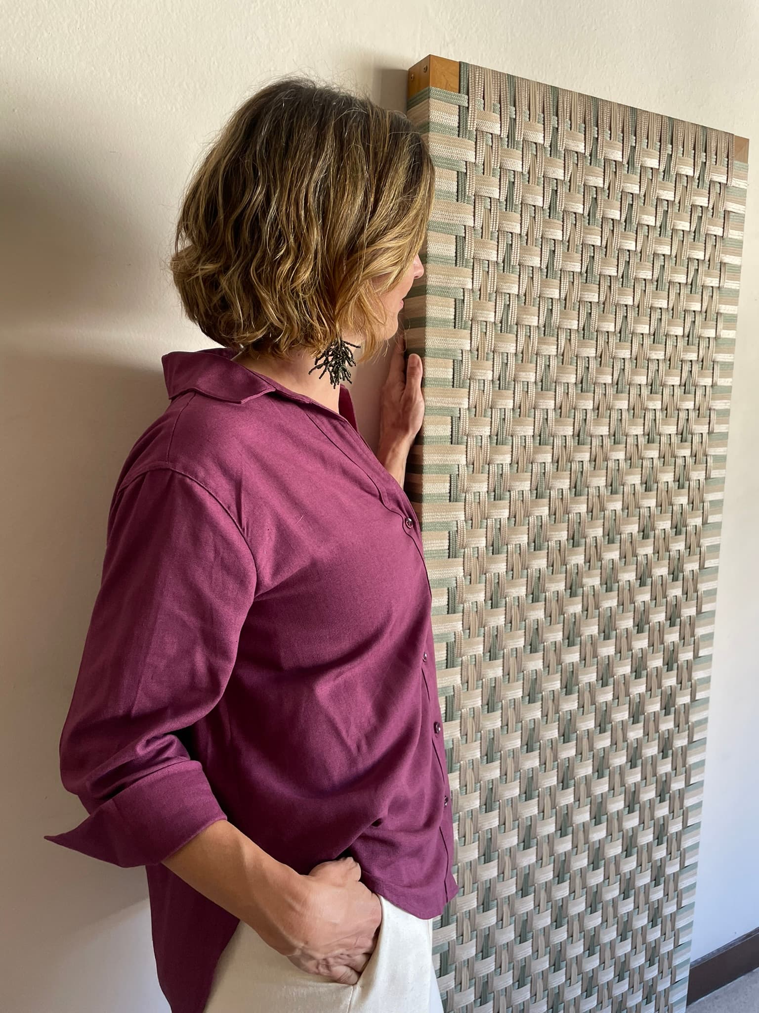 Carol Risi observando um painel tramado da Patuá
